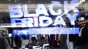 Black Friday sale sign reflected on the window of a clothing store with shoppers inside.