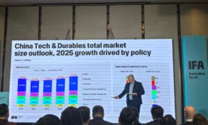 Business speaker presenting China tech and durables total market size outlook for 2025 on a large data slide at an IFA conference.