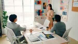 Team meeting in modern office with woman presenting colorful design boards to two colleagues at conference table
