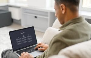 Man using a laptop with the ChatGPT interface open while sitting on a couch at home